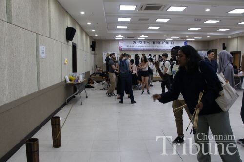 International students play "Tuho," a traditional Korean game of throwing arrows into a pot.