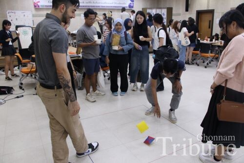 Students play a game of "Ttakjichigi," a traditional game where players try to flip each other's "Ttakji" by slapping it on the ground.