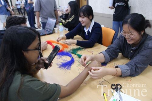 Students participating in the Chuseok event make bracelets.