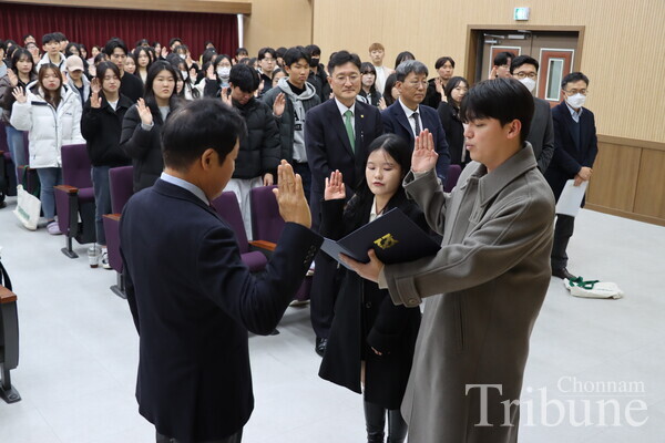 Two students take an oath, representing other students.