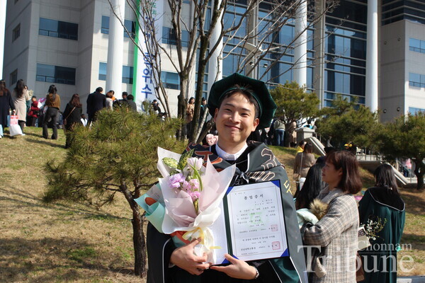 A graduating student pose for a picture in front of Minjumaru after the commencement ceremony on February 26.
