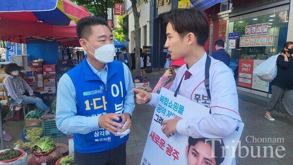 Kwak Seung-yong (right), former PeoplePower Party’s youth spokesperson, talkswith an official of another party duringthe 8th local election campaign.