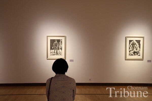 A Gwangju citizen views a woodcut print at the exhibition "May Art 2024: Woodcuts_Engrave the Spirit of the Age" on April 25.