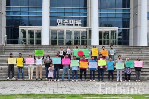 A group of Bangladeshi students hold up signs calling for the end of violence against student protesters over a quota system for government jobs at Chonnam National University on July 19.