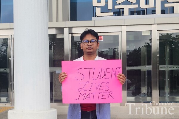 Farok Md Omar (Ph.D. Student, Interdisplinary Program of Global Diaspora Studies) poses for a picture holding a sign that says "Student Lives Matter" to call for the end of violence in Bangladesh.
