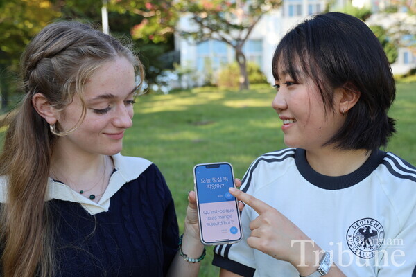 A foreign student and a Korean student converse using an AI language translator.