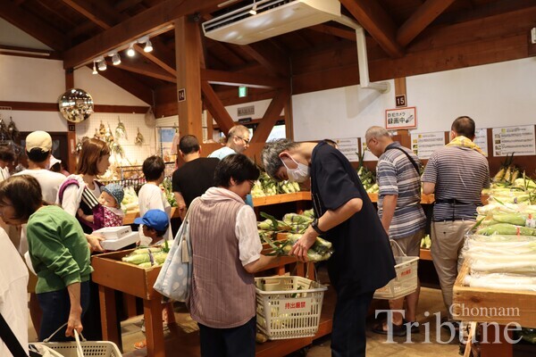 Customers shop for groceries at a farmer’s market in Denen Plaza on July 28.