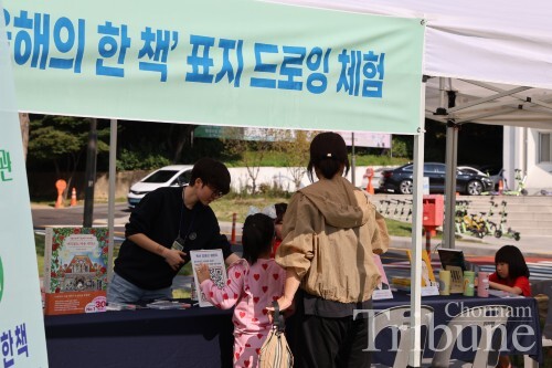 A child and her mother engage in a cultural activity at the outdoor library on October 12.