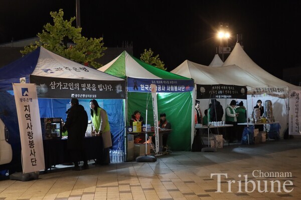 Many booths are set up, and volunteers provide supplies near the memorial altar.