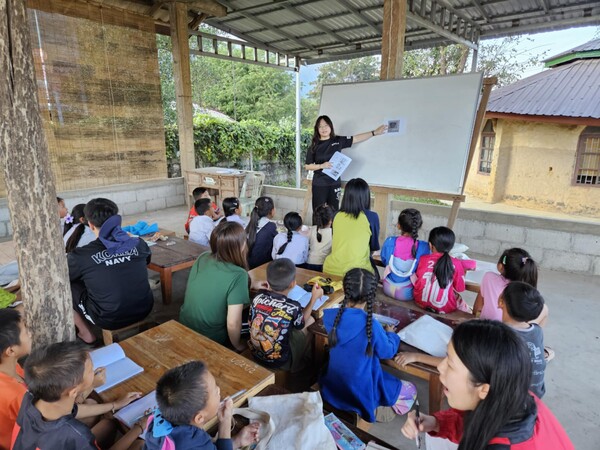 A woman explains in front of the Laos children.