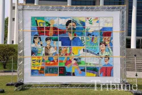 A mural, depicting the Gwangju Uprising of May 1980, displayed on a multi-panel canvas painted by students