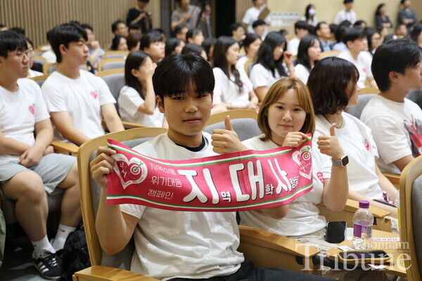 The members of the General Student Club Association at CNU hold a towel featuring the campaign slogan.